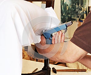 An upholsterer repairing an armchair with stapler