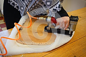 Woman working in upholstery workshop with pneumatic stapler.