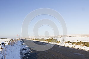 Upland country road in snow with wind farm