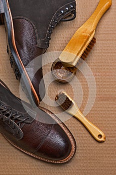 Upper Closeup View of Various Shoes Cleaning Accessories for Dark Brown Grain Brogue Derby Boots Made of Calf Leather Over Paper