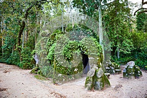 The upper entrance to the Initiation Well Inverted tower hided behind the mossy stones and vegetation in the park of Quinta da