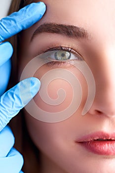 Upper eyelid reduction, double eye lid removal plastic surgery concept. Beautician doctor hands in gloves touching