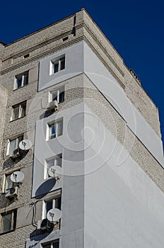 The upper part of an apartment building with many satellite dishes and air conditioning photo