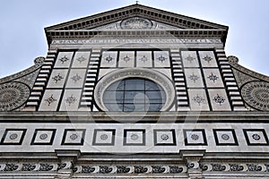 Upper part of the beautiful facade covered in white marble with black marble outline, of the church of Santa Maria Novella in Flor