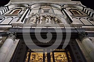 Upper part of the facade of the Baptistery of San Giovanni in Florence, with the golden door in the frame of two columns and the t