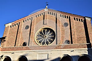 Upper part of the facade of the Church of the Hermits with the background of the blue sky and large rose window in Padua.