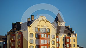 Upper part of interesting unusual red-yellow house-hotel with beautiful brown roof and towers of European style