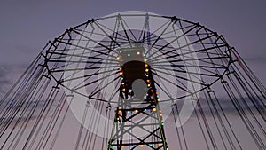 The upper part of moving chained carousel against twilight sky: slow motion