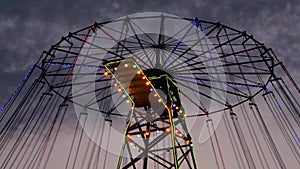 The upper part of moving chained carousel against twilight sky after sunset