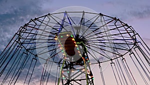 The upper part of moving chained carousel against twilight sky after sunset