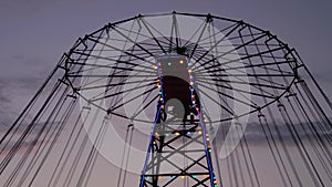 The upper part of moving chained carousel against twilight sky after sunset