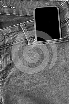 The upper part of old worn black jeans and a smartphone with a black screen