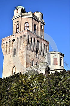 Upper part, protruding from the crowns of some trees and illuminated by the sun in the blue sky, of the Specola di Padova seat of