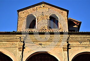 Upper part, with two windows on brick walls, of the facade of a historic building in via Cesarotti in Padua, next to the Basilica