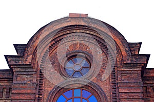 The upper part of the vintage building. A wall of dark red brick. Vintage round window.