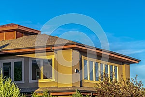 Upper storey of home with hip roof and brown wall against vibrant blue sky