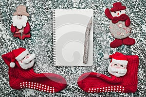 Upper, top, view from above of a notepad, wooden vintage pen, handmade snowman toy and Santa socks on gray marble background