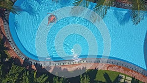 Upper view girl whirls on ring in tropical pool