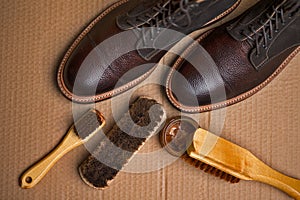 Upper View of Various Shoes Cleaning Accessories for Dark Brown Grain Brogue Derby Boots Made of Calf Leather Over Paper