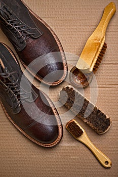 Upper View of Various Shoes Cleaning Accessories for Dark Brown Grain Brogue Derby Boots Made of Calf Leather Over Paper