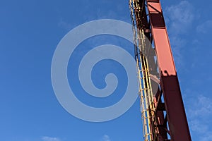 Upright metal girders with attached caged ladder against a blue sky, creative copy space