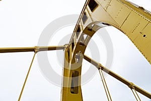 Upright support of a self anchored suspension bridge seen from below with cables against an overcast sky