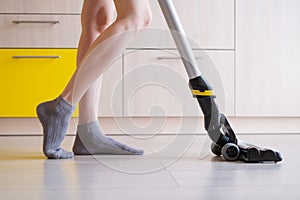 The upright vacuum cleaner cleans the laminate floor in the kitchen.