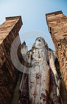 Uprisen angle view of old stand buddha statue in the ancient temple Thailand