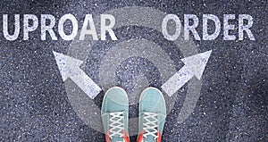 Uproar and order as different choices in life - pictured as words Uproar, order on a road to symbolize making decision and picking