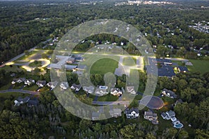 Upscale suburban homes at night with large backyards and green grassy lawns. Illuminated private residential houses in