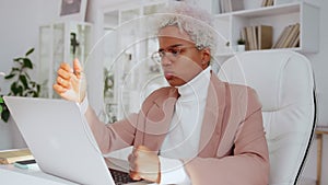 Upset African American business woman using laptop, doing difficult task