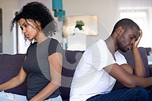 Upset African American couple ignore each other after quarrel
