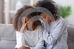 Upset african american mom hugging sad teen girl consoling supporting photo
