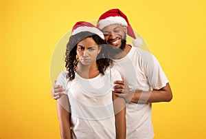 Upset african american woman and boyfriend comforting her on yellow studio background, copy space