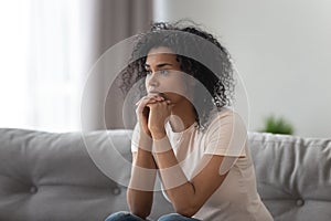 Upset African American woman thinking about problem at home alone