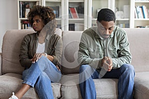 Upset african man and woman sitting on couch at home