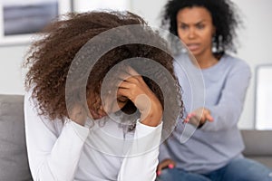 Upset african teenage girl turned back to angry mother scolding