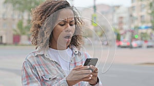 Upset African Woman Reacting to Loss on Smartphone Outdoor