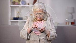 Upset aged female counting coins in hand, low pension income, retirement poverty