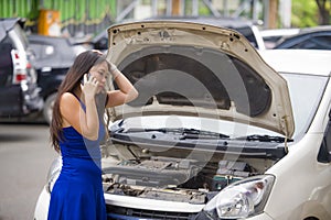 Upset Asian Korean woman in stress stranded on street suffering car engine failure having mechanic problem calling on mobile phone