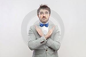 Upset attractive bearded man standing showing x sign, no way gesture, looking at camera.