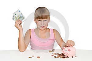 Upset baby girl with piggy bank isolated