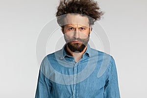 Upset bearded guy in denim shirt making a sad face and frowning