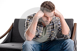 Upset bearded man sitting on sofa