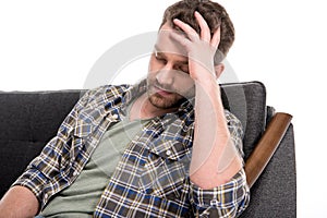 Upset bearded man sitting on sofa