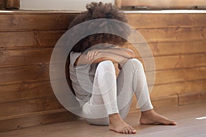 Upset biracial preschooler girl cry sitting on floor