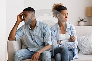 Upset Black Couple Avoiding Eye Contact Sitting On Couch photo
