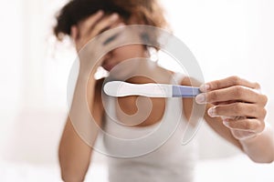 Upset black woman holding negative pregnancy test