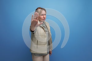 upset blond european lady in spring clothes with disagree gesture on blue background with copy space