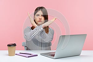 Upset bossy woman office worker sitting at workplace crossing hands showing x sign, rejecting and finishing sexual harassment at